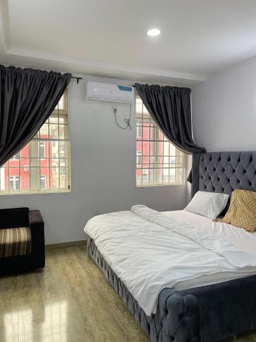 a bedroom with a large bed and two windows at Kells Savannah Apartment in Gwarinpa, Abuja in Abuja