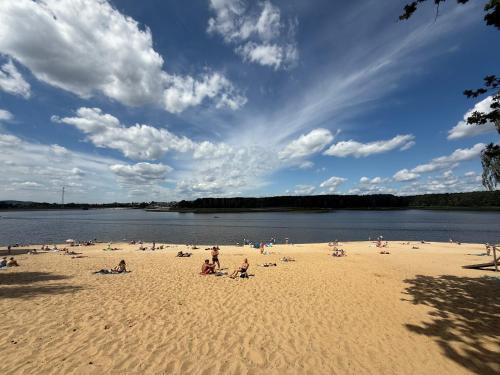 a group of people on a beach near a body of water at Family & Business Sauna Apartments No1 Leśny nad Zalewem Cedzyna Unikat - 3 Bedroom with Private Sauna, Bath with Hydromassage, Terrace, Garage, Catering Options in Kielce