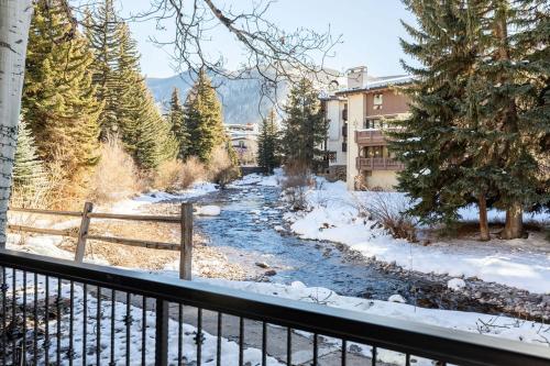 a river with snow on the ground next to a fence at Talisman Condos by Vail Realty in Vail