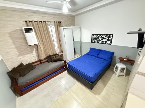 Un dormitorio con una cama azul y una ventana. en Pies en la esquina de arena del fuerte VIII, en Praia Grande