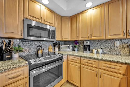 a kitchen with wooden cabinets and a stove and microwave at Papakea C405 in Kahana