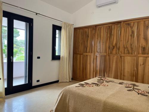 a bedroom with a bed and wooden cabinets at Villa Cocomerara Tas24 in Calimera