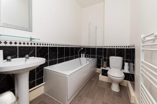 ein Badezimmer mit Badewanne, Toilette und Waschbecken in der Unterkunft Sea Shore Apartment in Llandudno