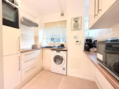 a white kitchen with a washing machine in it at Self-catering Apartment in the Heart of London Victoria in London