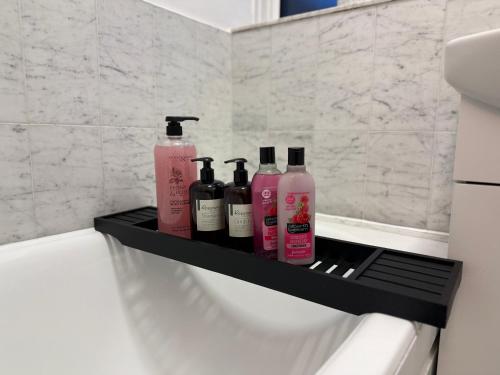 a black shelf with four bottles on it in a bathroom at Self-catering Apartment in the Heart of London Victoria in London