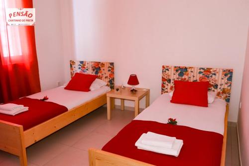 two beds in a room with red and white sheets at Pousada Cantinho de Preta in Seladinha