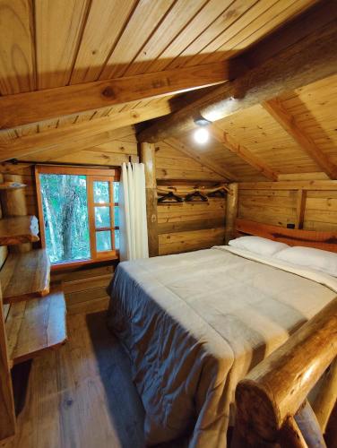 a bedroom with a bed in a log cabin at sítio Refúgio do Barro Branco in São Pedro de Alcântara