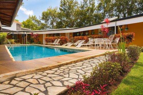 a swimming pool with a table and chairs next to a house at Hotel Puerta del Sol - San Jose Airport in San José