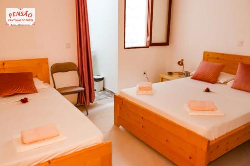 a bedroom with two beds and a chair at Pousada Cantinho de Preta in Seladinha