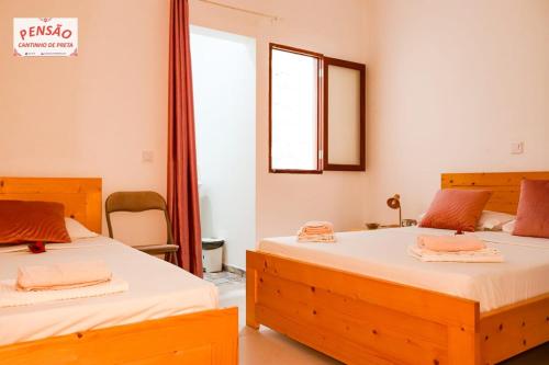 a bedroom with two beds and a window at Pousada Cantinho de Preta in Seladinha