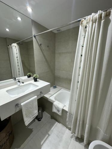 a bathroom with a sink and a tub and a shower curtain at Raíz Urbana in Tandil