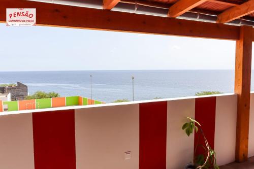 a white and red wall with the ocean in the background at Pousada Cantinho de Preta in Seladinha