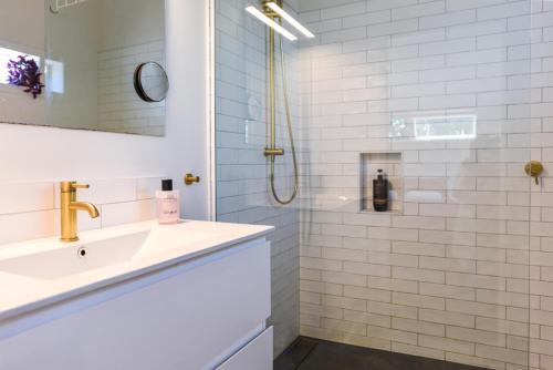 a white bathroom with a sink and a shower at La Maison Soleil - Waiheke Island in Waiheke Island