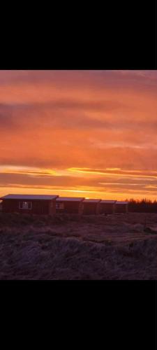 a sunset with a building in the middle of a field at Uxahryggur in Hvolsvöllur