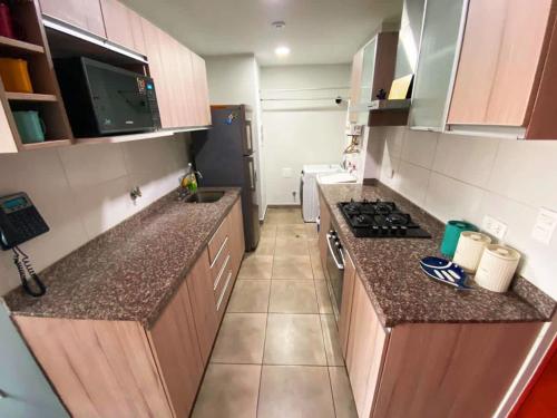 une petite cuisine avec des comptoirs en granit et une cuisinière dans l'établissement Appealing 3BR with Beautiful View in Magdalena, à Lima
