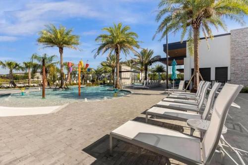 a row of white lounge chairs in front of a pool at Experience Luxury In Your 11 En-suites Mansion in Orlando