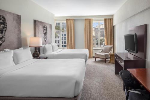 a hotel room with two beds and a flat screen tv at Crowne Plaza New Orleans French Qtr - Astor by IHG in New Orleans