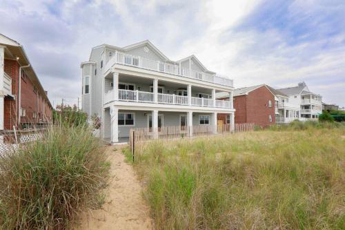 ein großes weißes Haus am Strand mit Häusern in der Unterkunft Sojourn Dune Cottage Beach Front Bliss 3 BR 3 BA in Norfolk