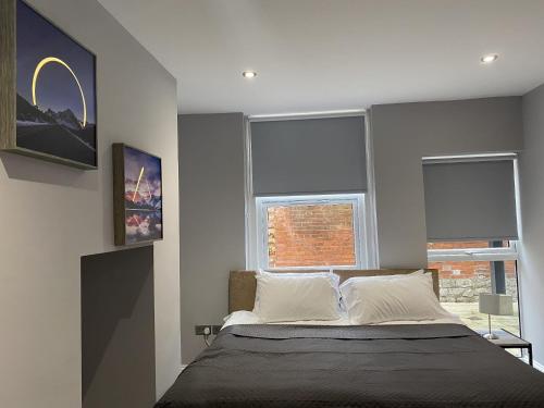 a bedroom with a large bed with two windows at Chic Maidstone getaway in Maidstone
