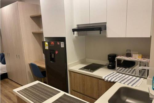 a kitchen with a black refrigerator and a sink at Hermoso Apartaestudio LOFT in Bogotá