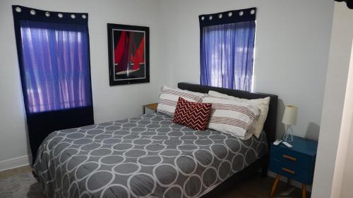 a bedroom with a bed and two windows at Charming Historic Home with Modern Comforts in Opa-locka