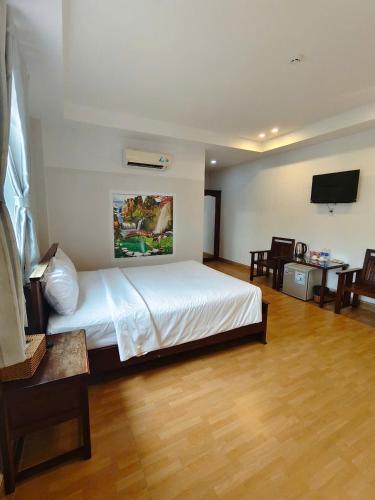 a bedroom with a white bed and a television at Phú Quốc Center Hotel in Phu Quoc