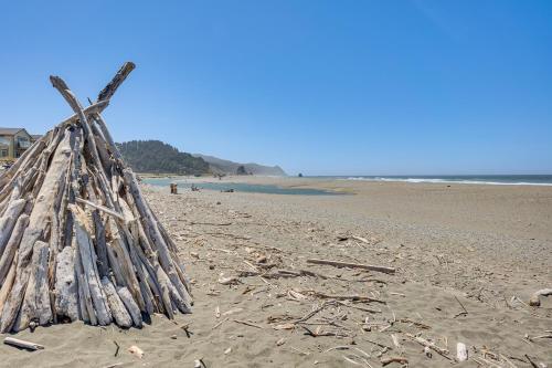 a pile of sticks on a sandy beach at Steps to Shore Home with Hot Tub in Gold Beach in Gold Beach