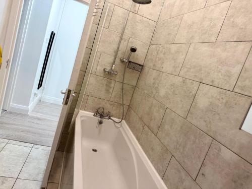 a bathroom with a tub and a shower with tiles at The Botanica, Stylish Edgbaston Escape with Garden Charm in Birmingham