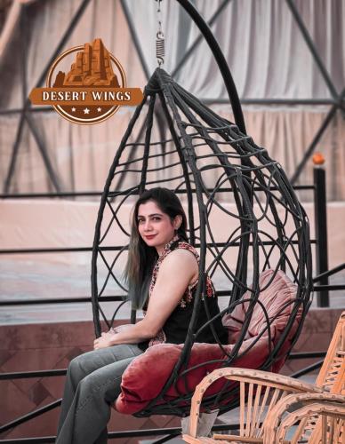 a woman is sitting in a hanging chair at RUM WINGS BUBBLES lUXURY CAMP in Wadi Rum