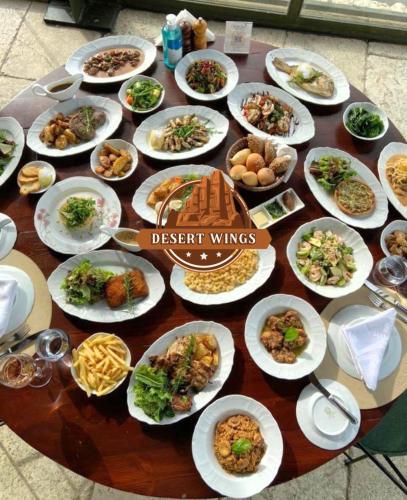 a table with many plates of food on it at RUM WINGS BUBBLES lUXURY CAMP in Wadi Rum
