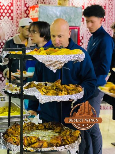 a man standing next to a rack of food at RUM WINGS BUBBLES lUXURY CAMP in Wadi Rum