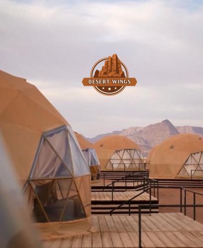 a row of domes with a sign that reads desert villages at RUM WINGS BUBBLES lUXURY CAMP in Wadi Rum
