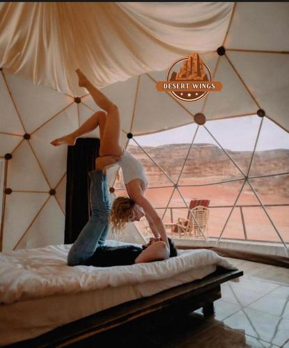 a woman on a bed with her legs in the air at RUM WINGS BUBBLES lUXURY CAMP in Wadi Rum