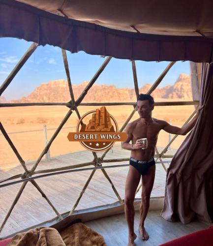 a man standing in a tent in front of a window at RUM WINGS BUBBLES lUXURY CAMP in Wadi Rum