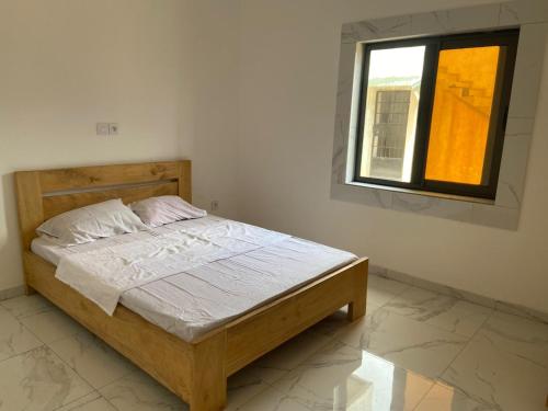 a bedroom with a wooden bed with a window at Guest House Abomey Calavi Ahossougbéta in Abomey-Calavi