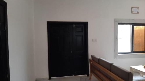 a black door in a room with a bench at Guest House Abomey Calavi Ahossougbéta in Abomey-Calavi
