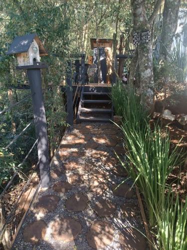 a walkway with a bird house and a tree at Treiler experiência na floresta in Iomerê