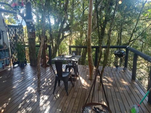 a wooden deck with a table and chairs on it at Treiler experiência na floresta in Iomerê