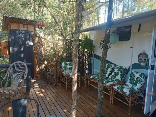 a porch of a house with a deck with chairs at Treiler experiência na floresta in Iomerê