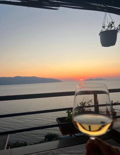 a glass of wine with the sunset in the background at Hotel Kappa3 Villas in Vlorë
