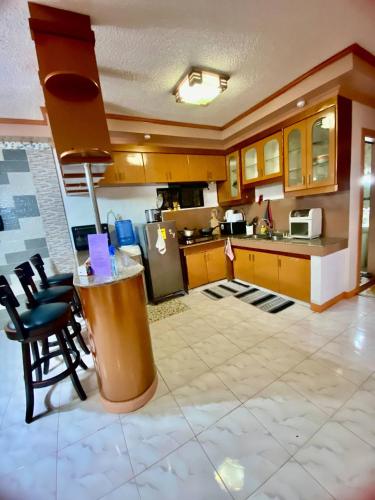 a large kitchen with a counter and some chairs at Lens Staycation 3BDR-2BR-Downstairs ,NetflixWifi in Panabo