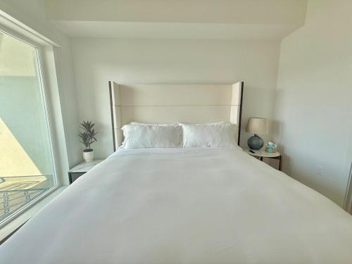 a large white bed in a white room with a window at Westwood Penthouse 3 Bedroom 2 Bath w Gym, Balcony, Parking in Los Angeles