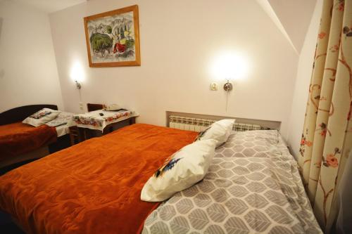 a small bedroom with a bed with an orange blanket at Apartamenty Willa Anna in Poronin