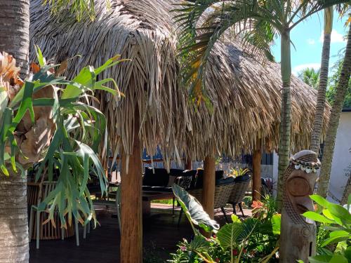 a restaurant with a straw umbrella and chairs and palm trees at Tiki Ora Lodge - VARUA in Bora Bora