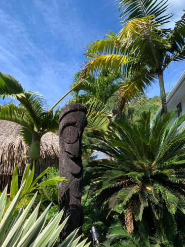 a statue of a palm tree next to palm trees at Tiki Ora Lodge - VARUA in Bora Bora