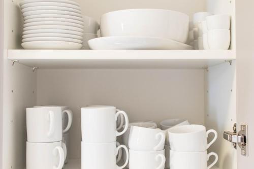a cupboard filled with white dishes and plates at Altstadt Suite in Weimar