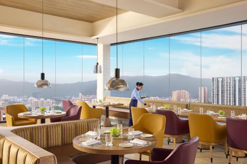 a man standing in a restaurant with tables and chairs at Vivanta Thane LBS Road in Thane