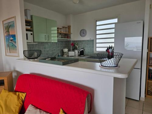 une cuisine avec un comptoir blanc et une serviette rouge dans l'établissement L'Oiseau de Paradis - Vue Mer Panoramique, à Les Trois-Îlets