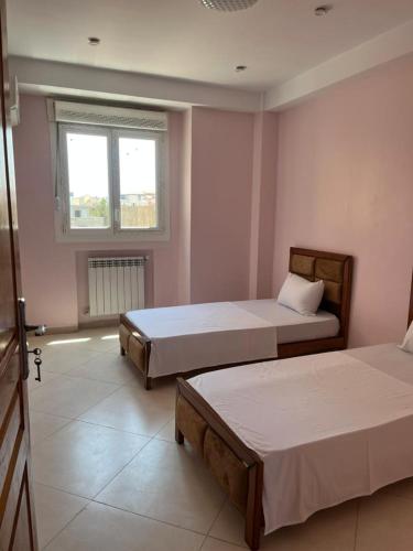 a bedroom with two beds and a window at Ain Taya residency in 'Aïn Taya