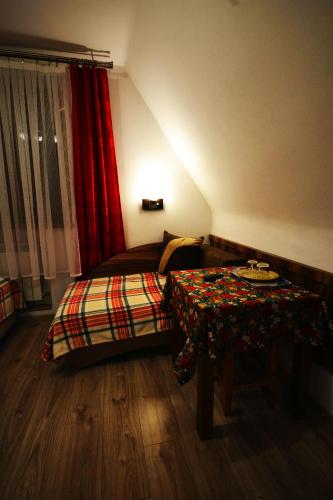 a bedroom with a bed with a table and a red curtain at Apartamenty Willa Anna in Poronin